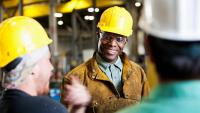 A smiling man wearing a hard hat and safety glasses